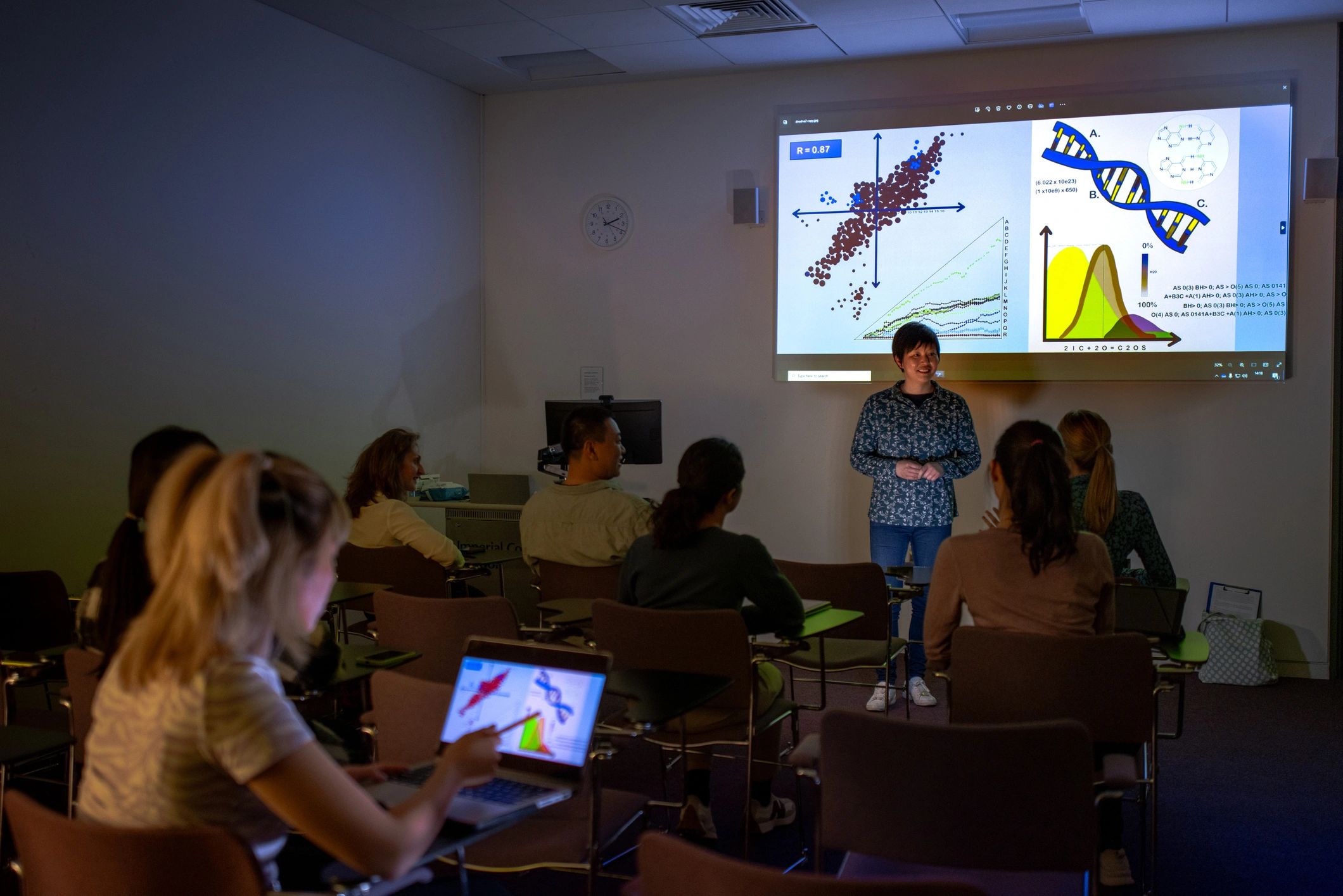 Students engaged in a lecture with a smiling instructor